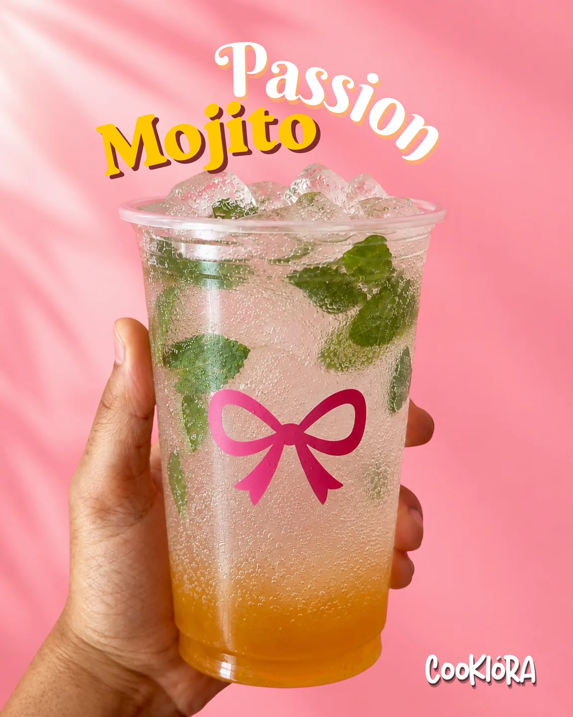 A hand holding a Passion Mojito, golden at the bottom