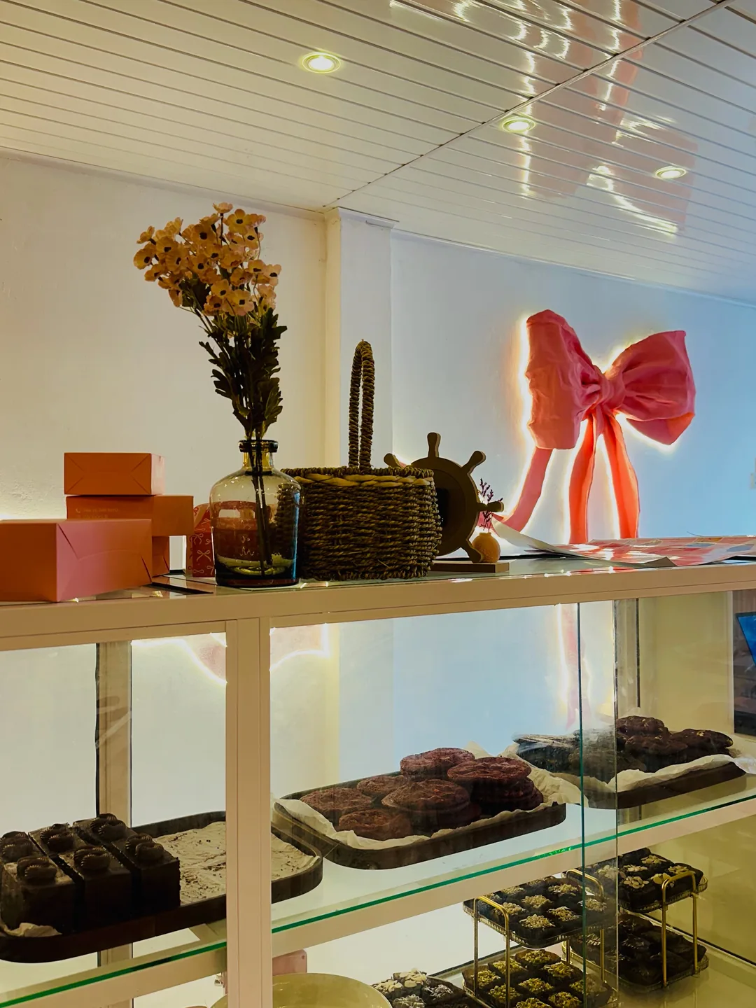 Inside Cookiora: a glass counter of brownies below a big pink bow