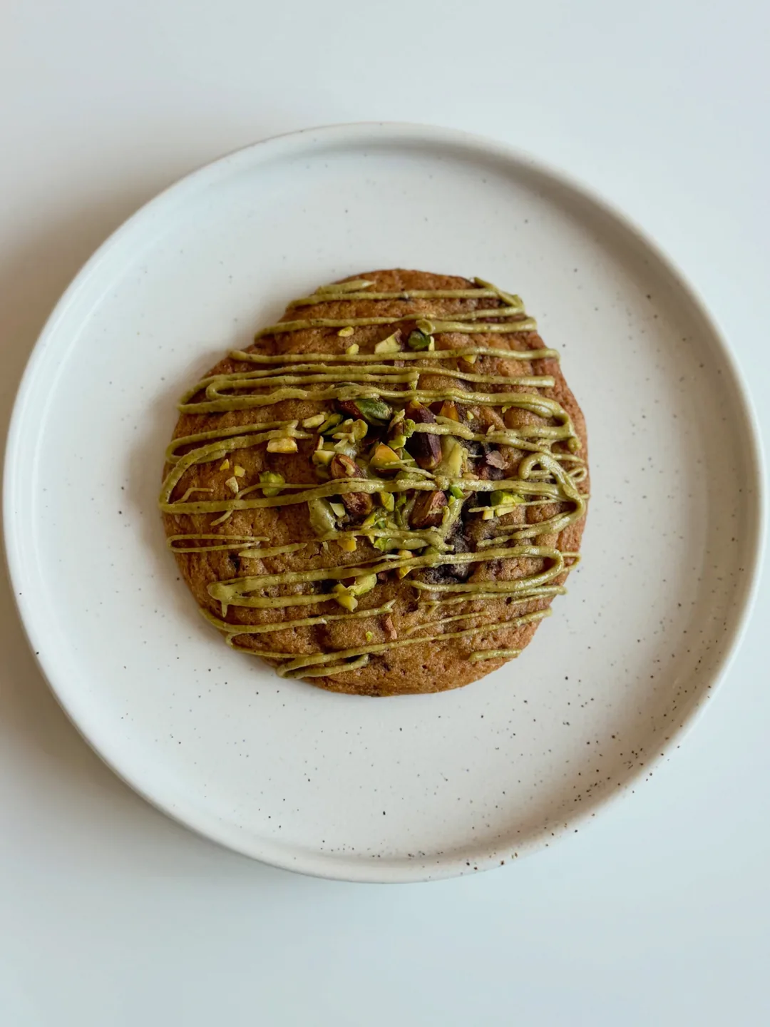 Pistachio cookie on a white plate, from the Cookiora Instagram post