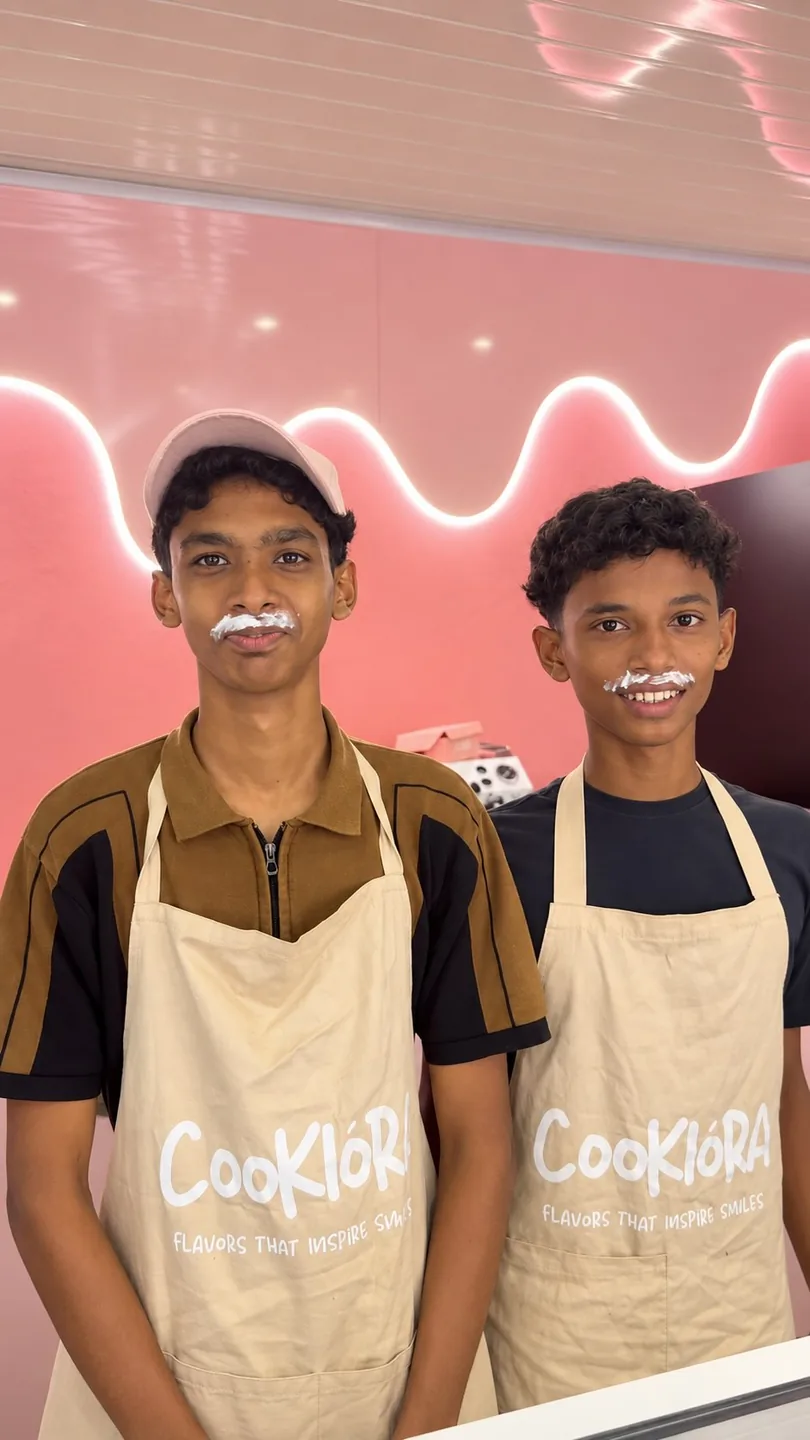 Two young men in Cookiora aprons with milk moustaches